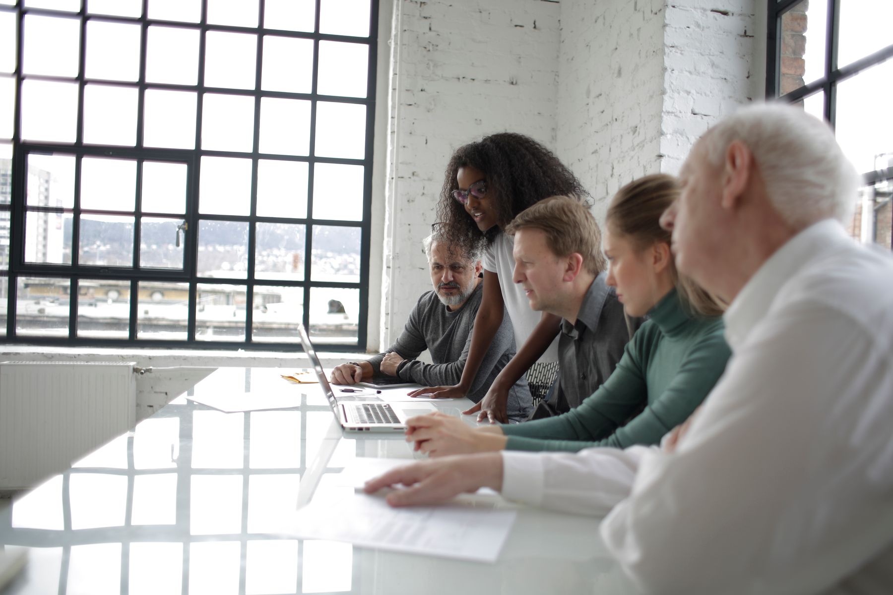 A cross-functional team reviewing work together around a laptop.